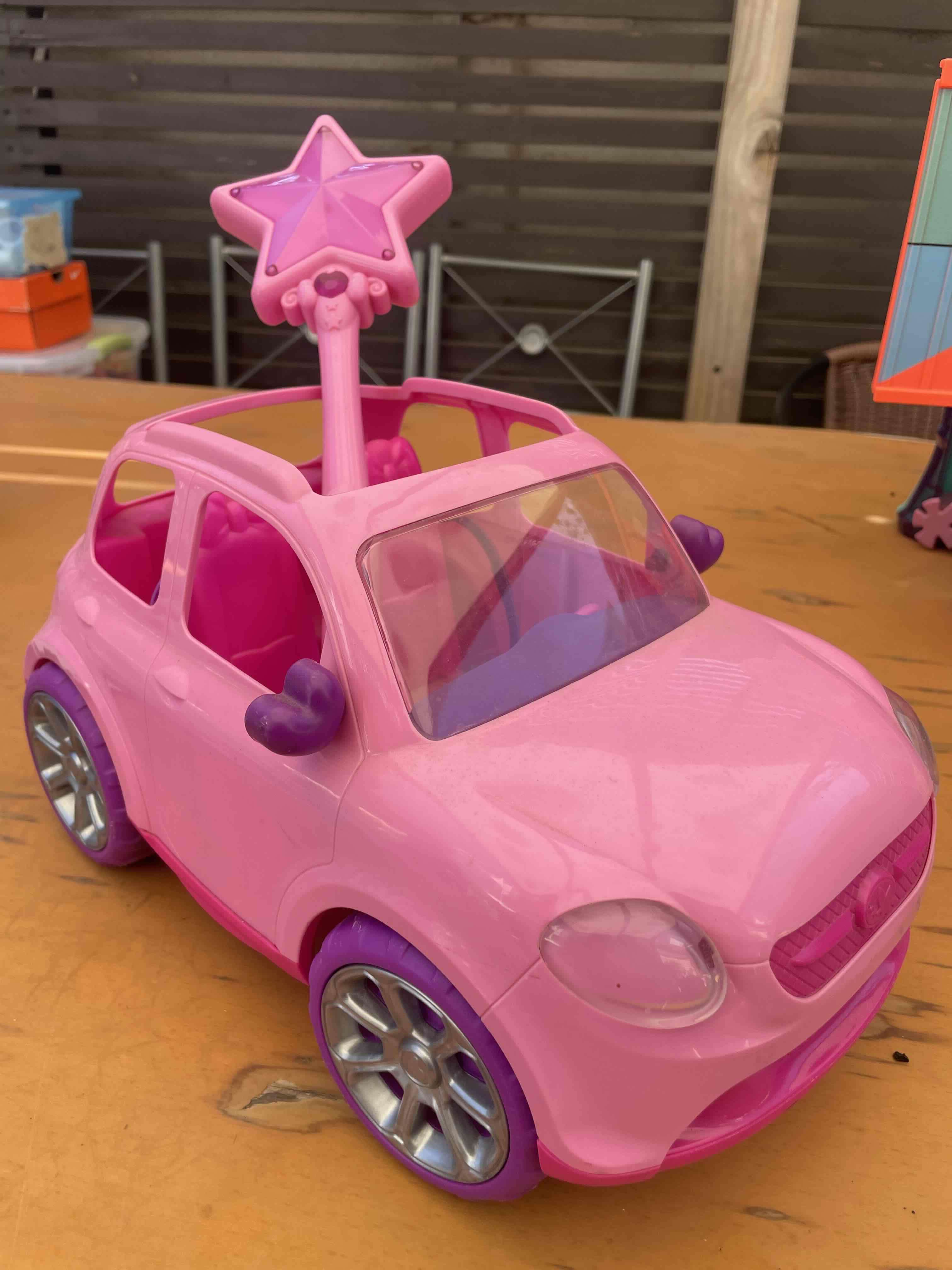 Auto de juguete rosa con varita a control remoto.