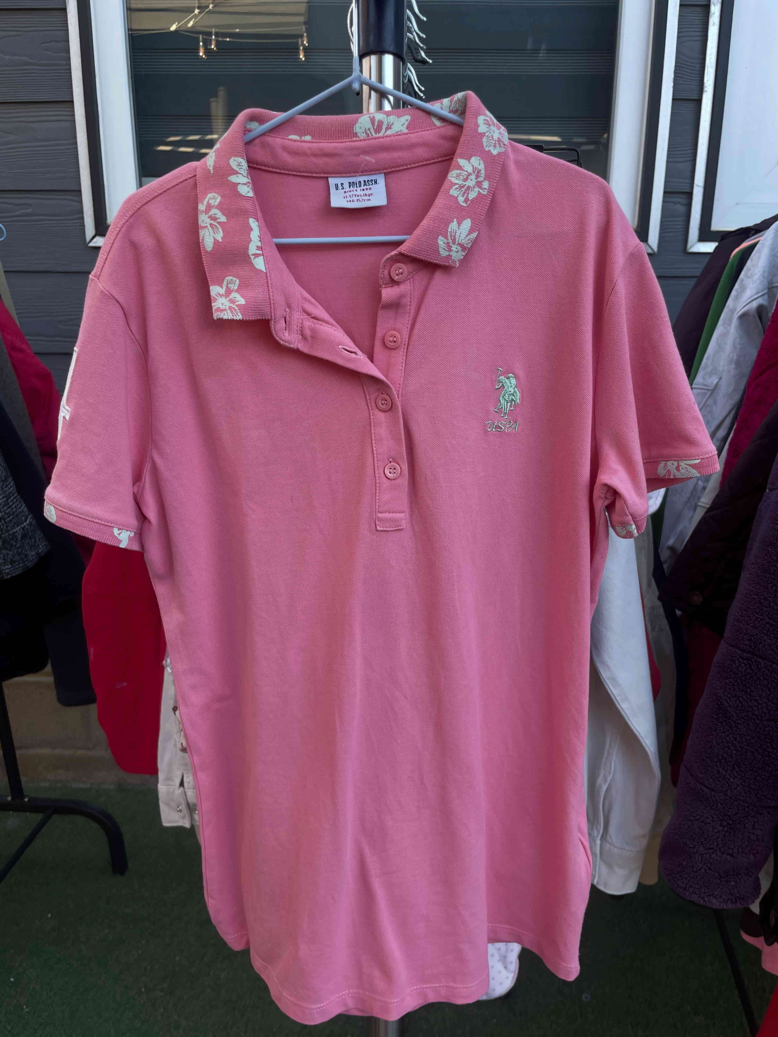 Polera Polo Assn rosa con flores en el cuello.
