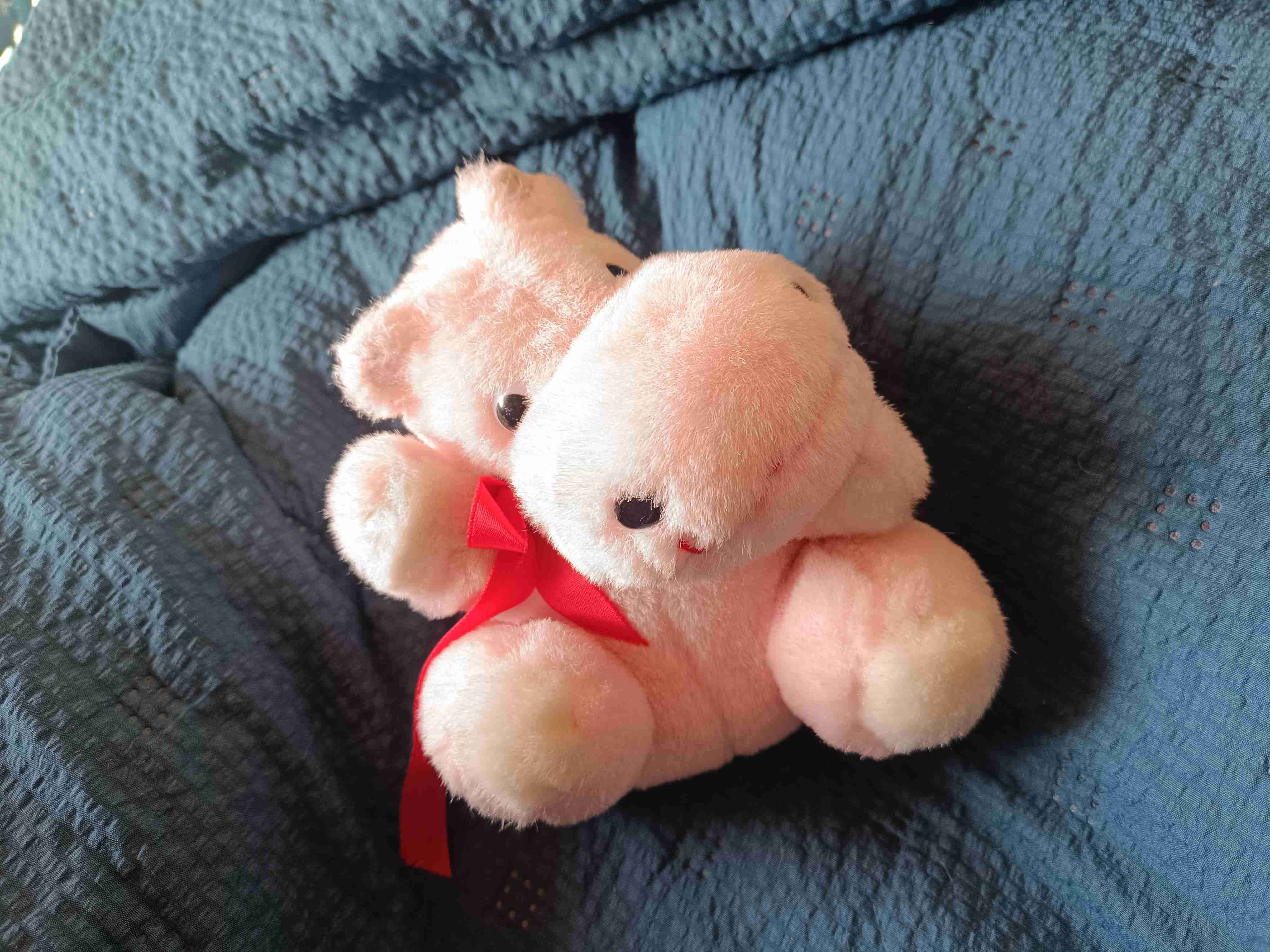Peluche de hipopótamo rosado con lazo rojo