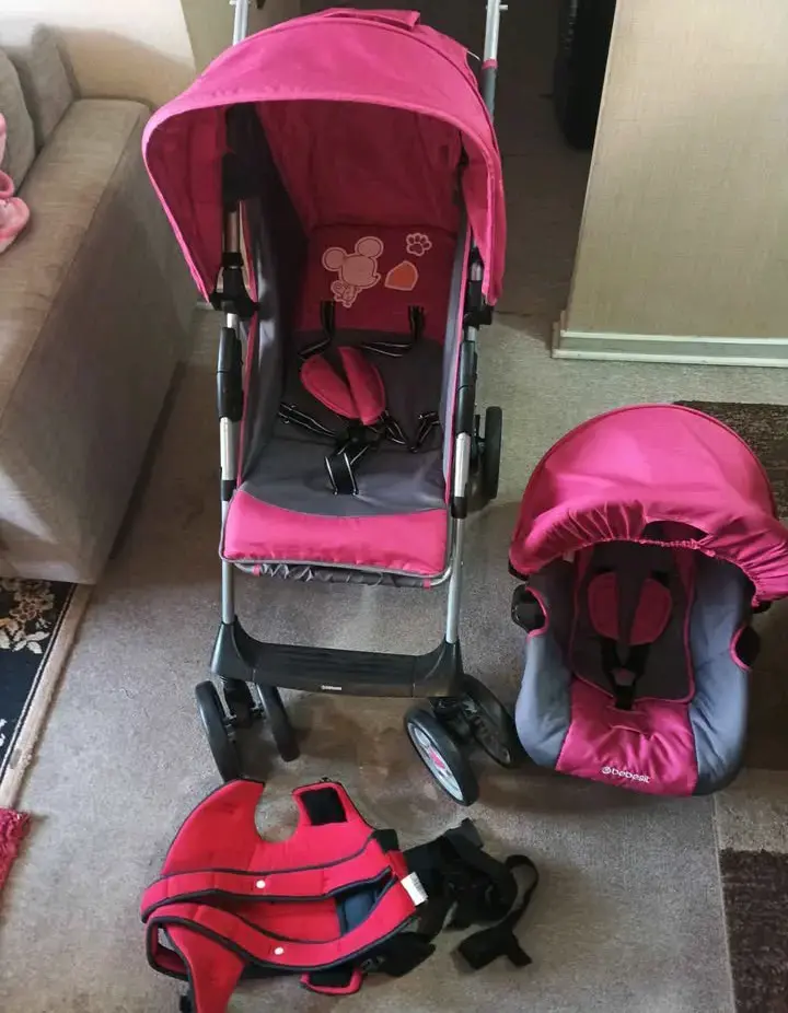 Coche de bebé rosa con accesorios