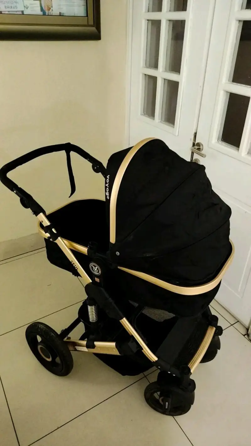 Coche de bebé negro y dorado
