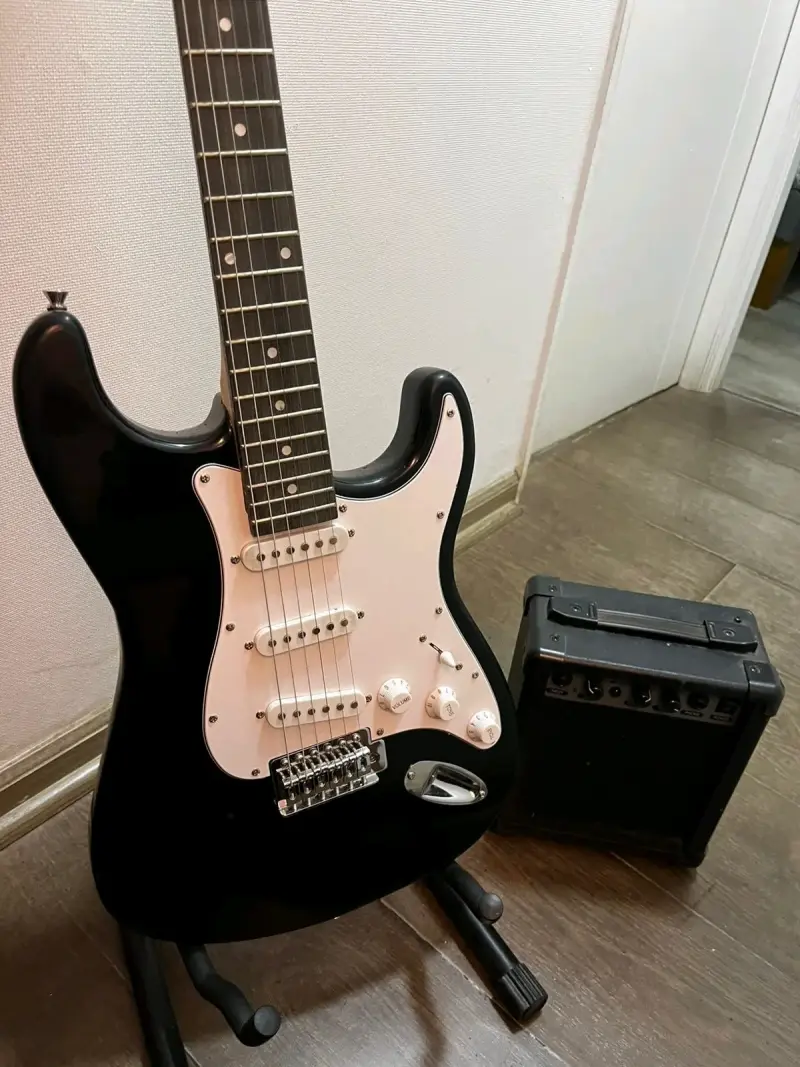 Guitarra eléctrica negra con amplificador - 1