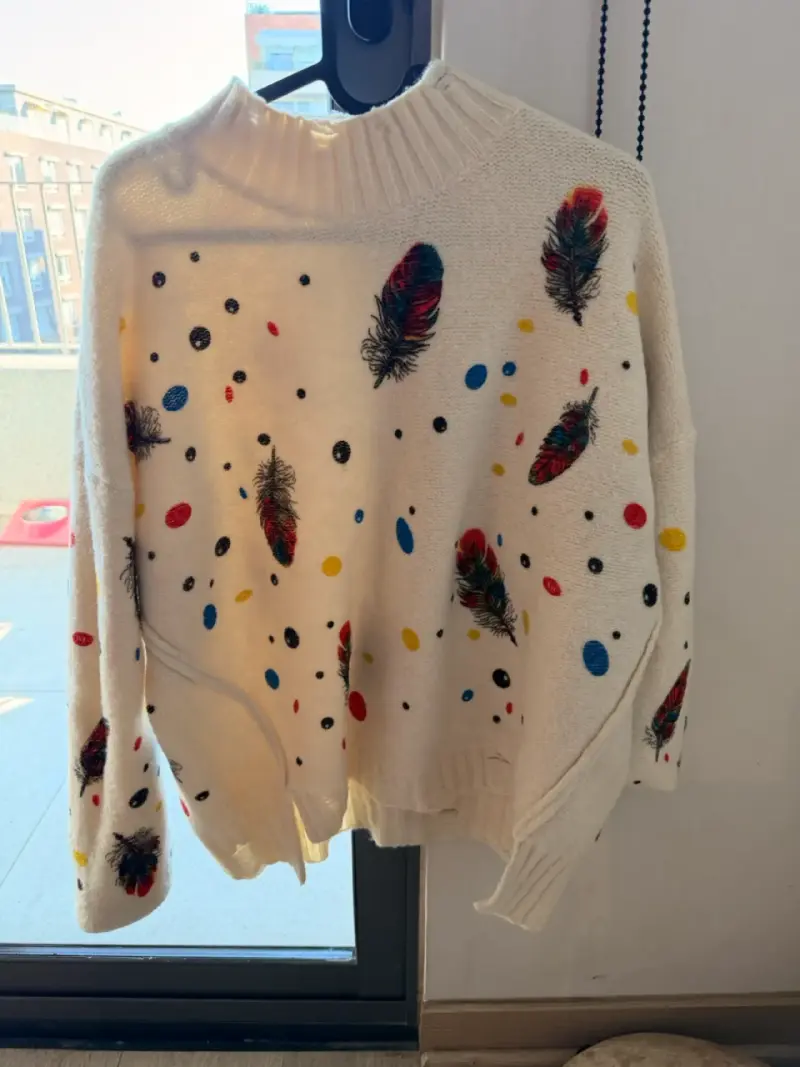 Suéter blanco con plumas y puntos coloridos
