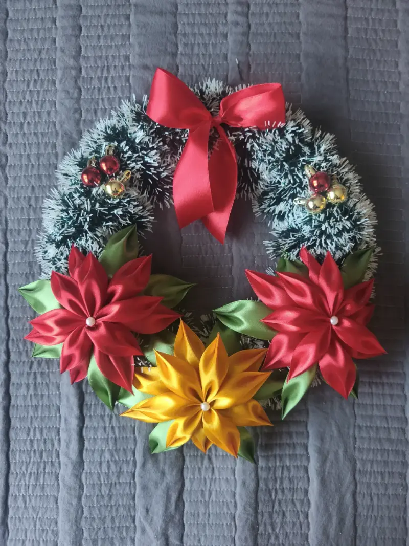 Corona navideña con flores de tela y lazo rojo