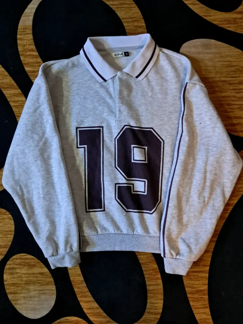 Polerón gris con número 19 y cuello polo