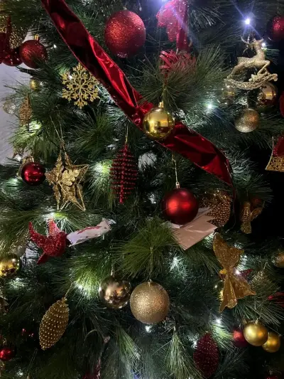 Árbol de Navidad decorado con adornos dorados y rojos - miniatura 1