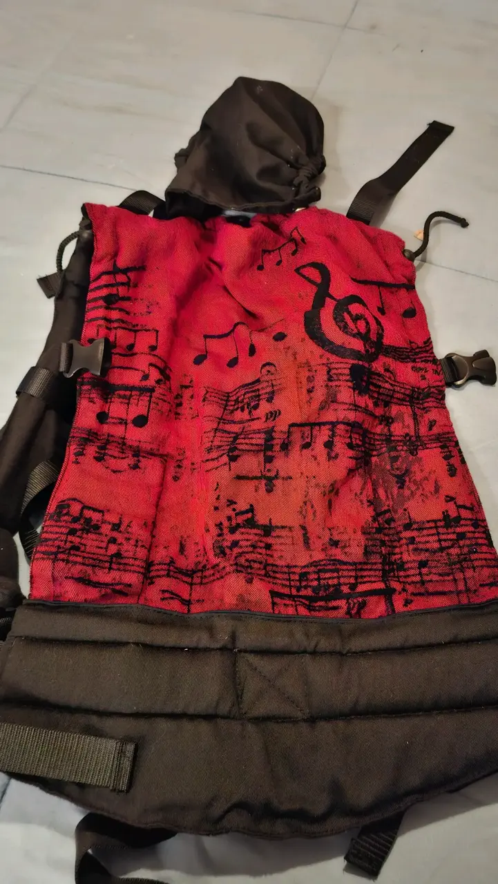 Mochila portabebés roja con diseño musical