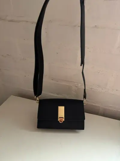 Cartera negra elegante con cierre dorado - miniatura 1