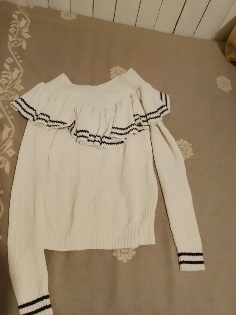 Suéter blanco con volantes y detalles negros
