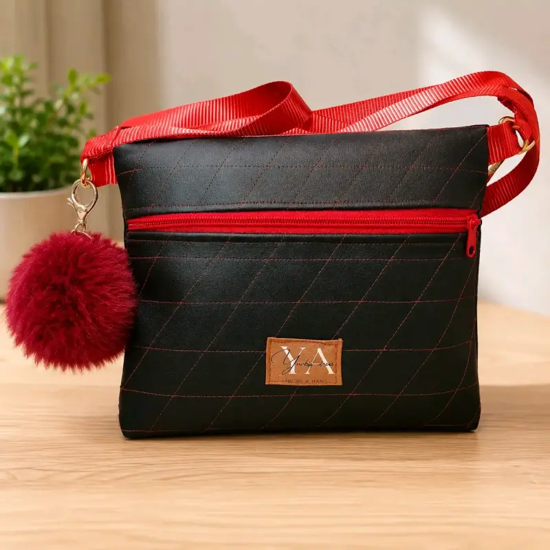 Cartera negra con correa roja y pompón