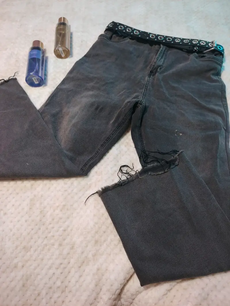 Jeans negros desgastados con cinturón decorativo
