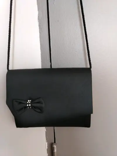 Elegante cartera de mano negra con lazo decorativo - miniatura 1