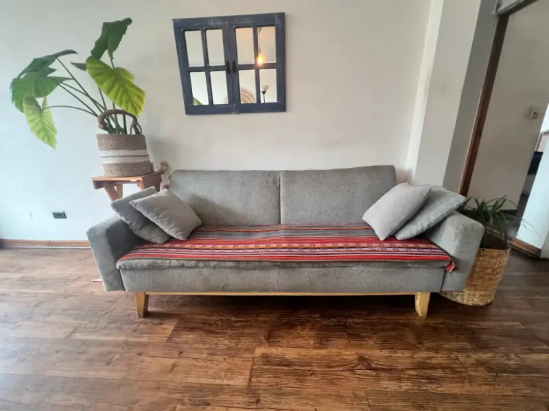 Sofá gris moderno con cojines y manta decorativa - 1