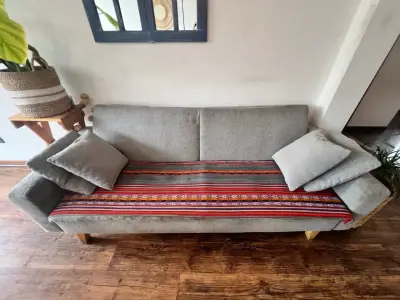 Sofá gris moderno con cojines y manta decorativa - miniatura 2