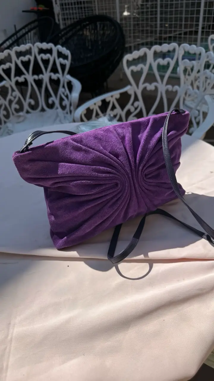 Cartera de mano morada con diseño plisado