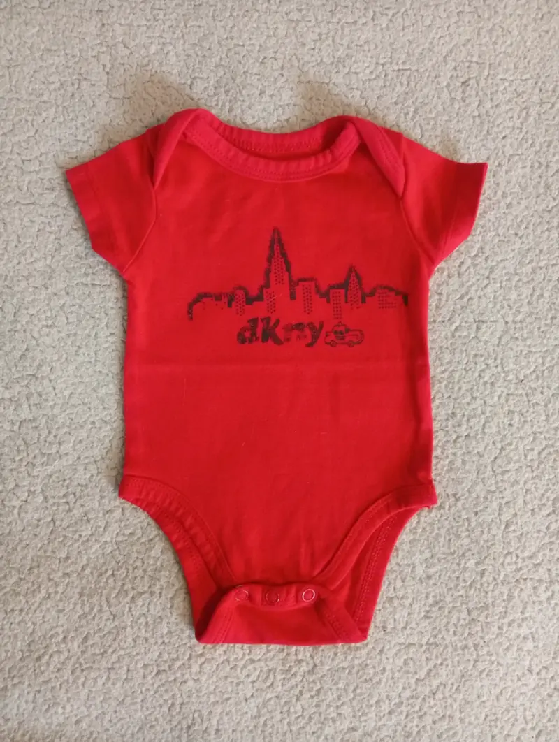 Body de bebé rojo DKNY con diseño de ciudad