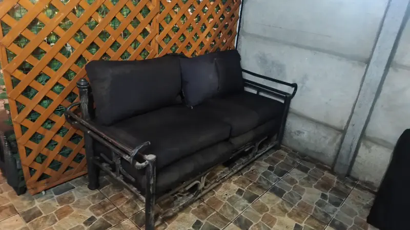 Sofá de jardín de metal con cojines negros