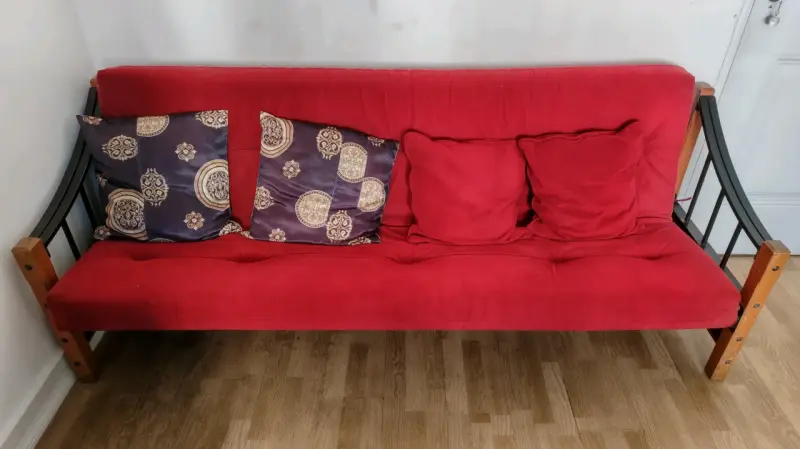 Sofá cama rojo con cojines decorativos