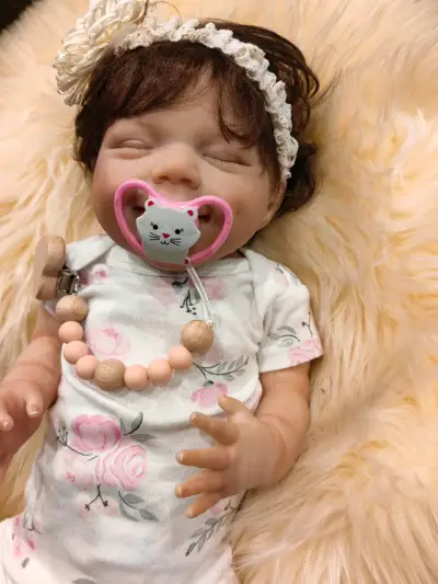 Muñeca reborn con chupete y ropa floral - miniatura 1