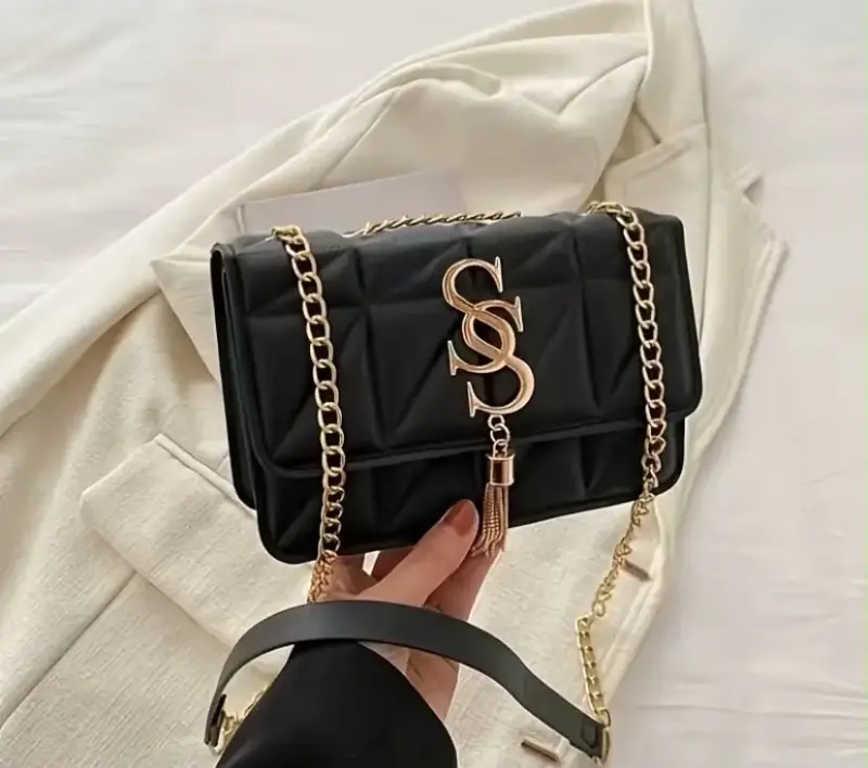 Cartera negra con cadena dorada y logo decorativo