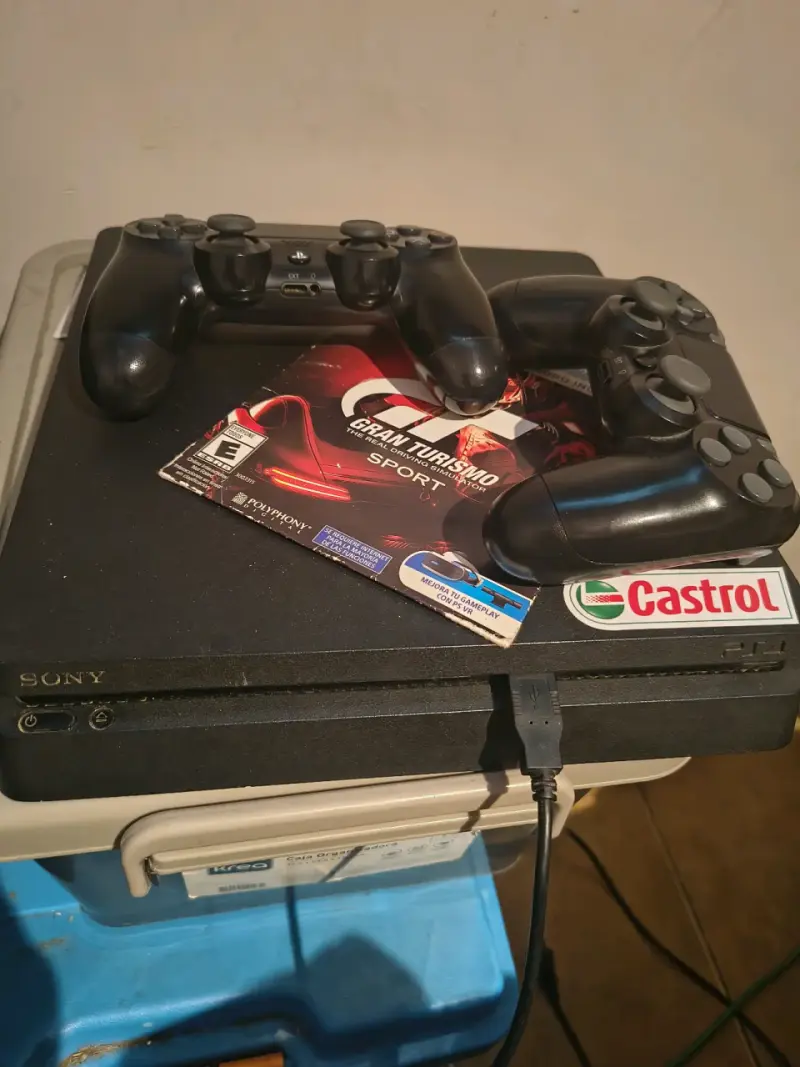 Consola PlayStation 4 con dos controles y juego Gran Turismo Sport