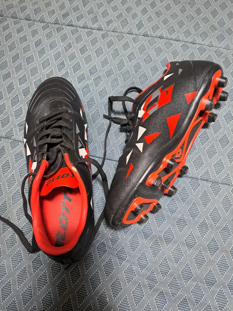 Botines de fútbol negros y rojos con diseño geométrico