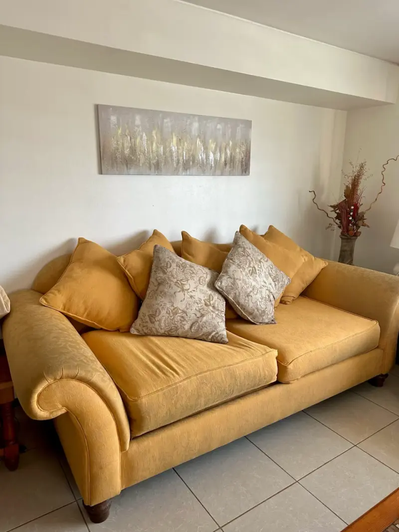 Sofá de tres plazas amarillo con cojines decorativos - 1