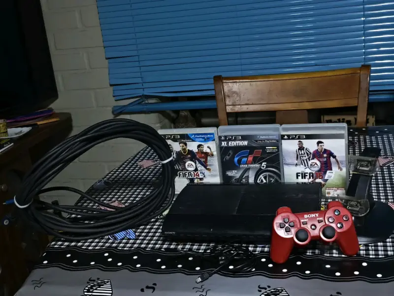 Consola PlayStation 3 con juegos y control rojo - 1