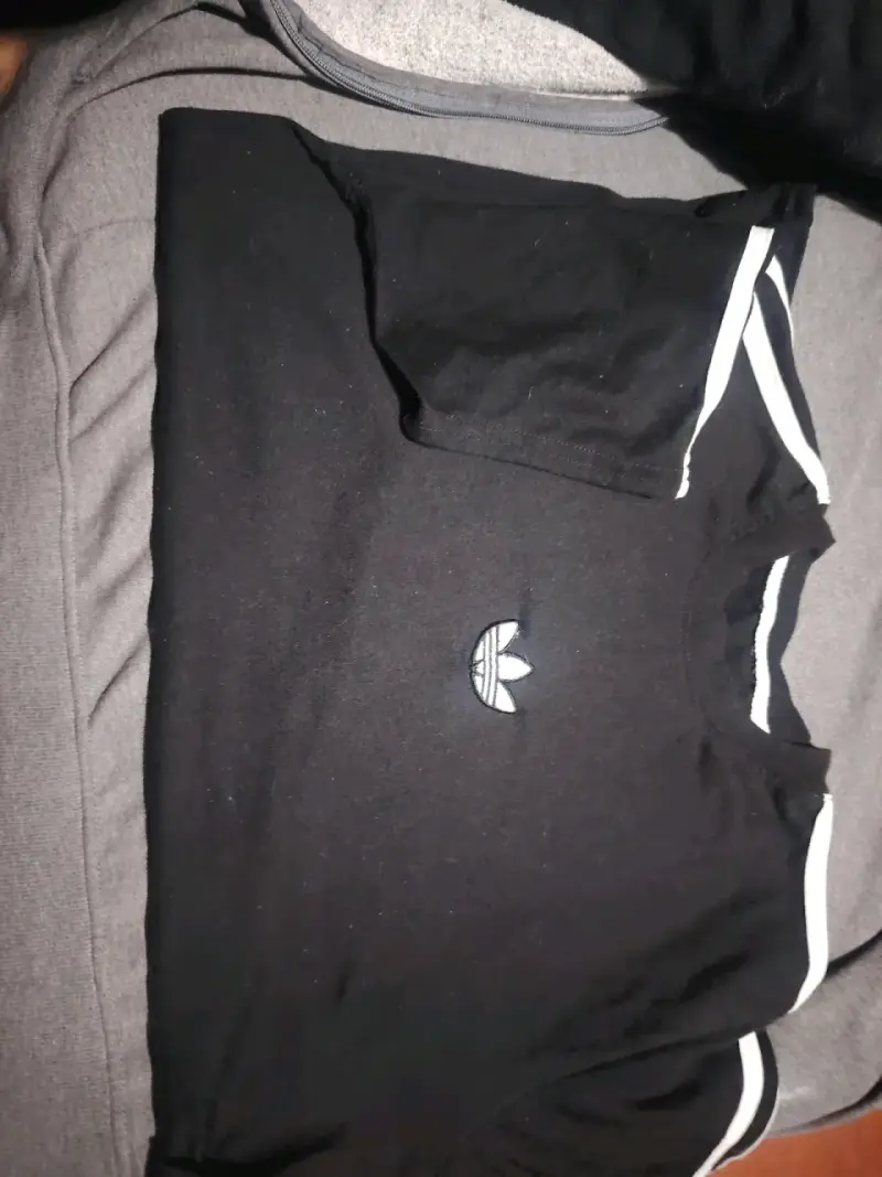 Polera negra Adidas con logo y detalles blancos