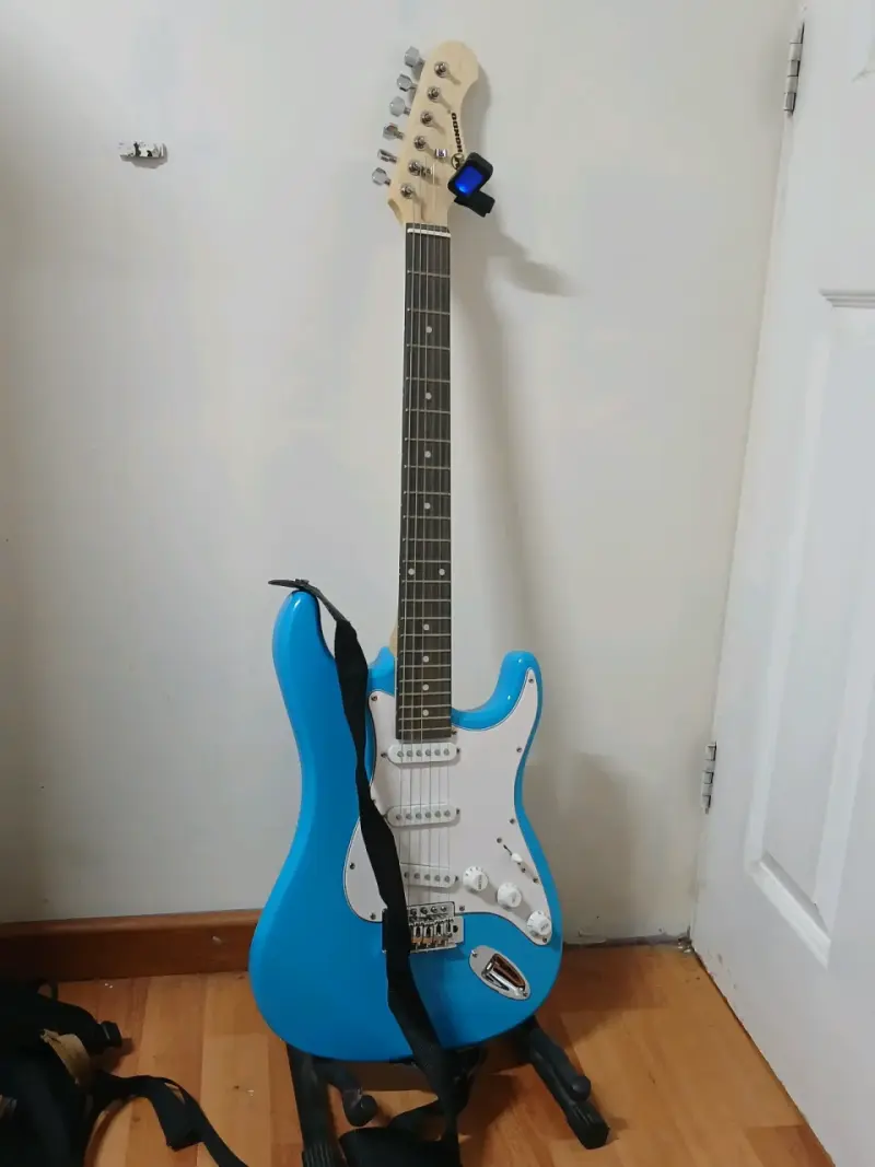 Guitarra eléctrica azul con amplificador y soporte