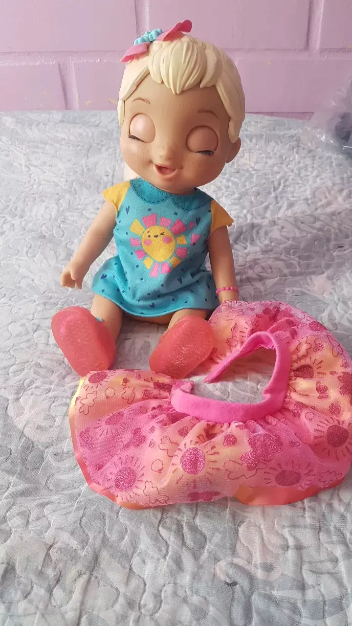 Muñeca bebé con vestido azul y accesorio rosa - 1