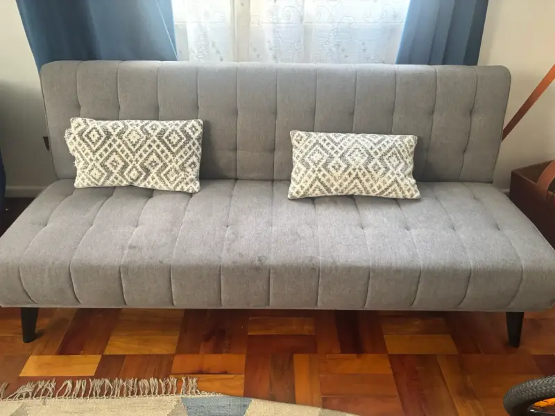 Sofá cama gris moderno con cojines decorativos