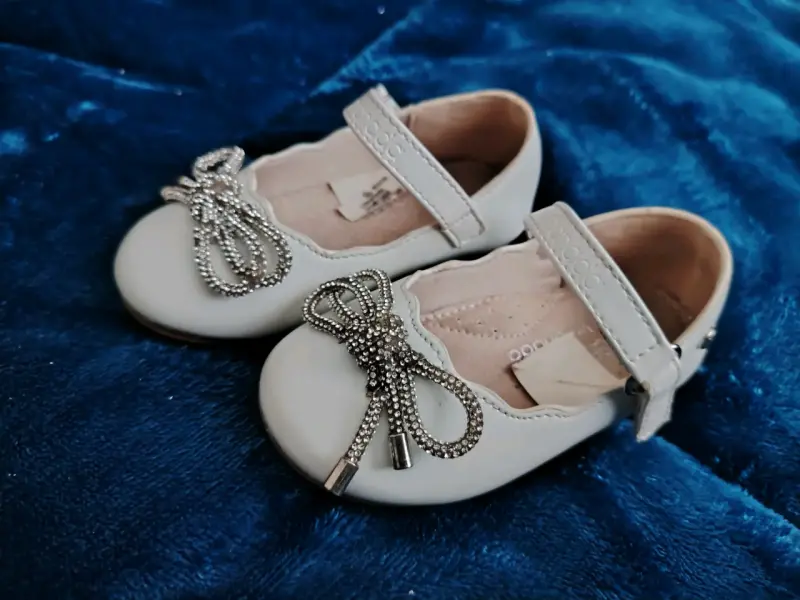 Zapatos de bebé blancos con lazo decorativo