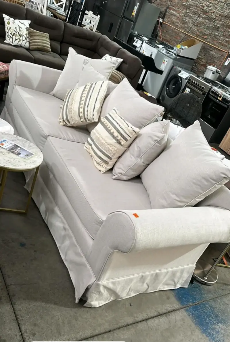 Sofá beige de tres plazas con cojines decorativos