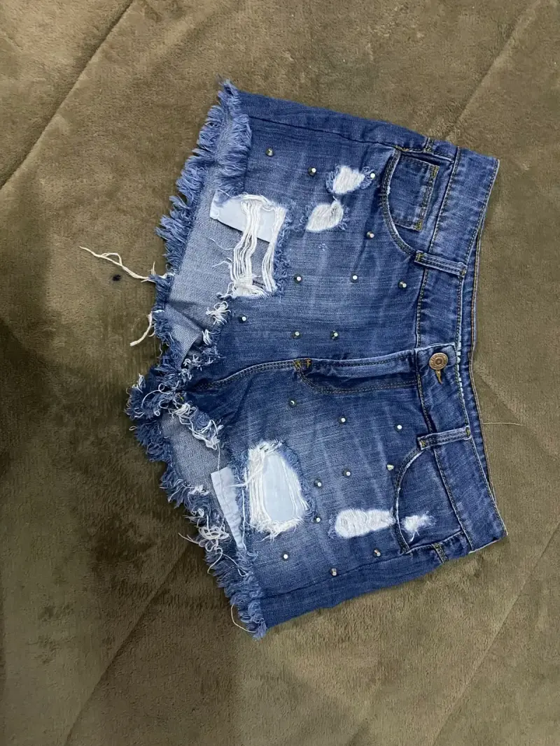 Shorts de mezclilla con detalles desgastados y tachas