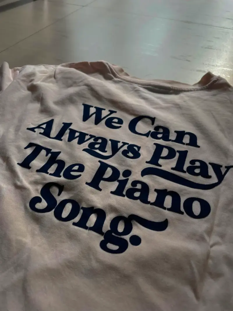 Polera blanca con estampado frontal "We Can Always Play The Piano Song" - 1