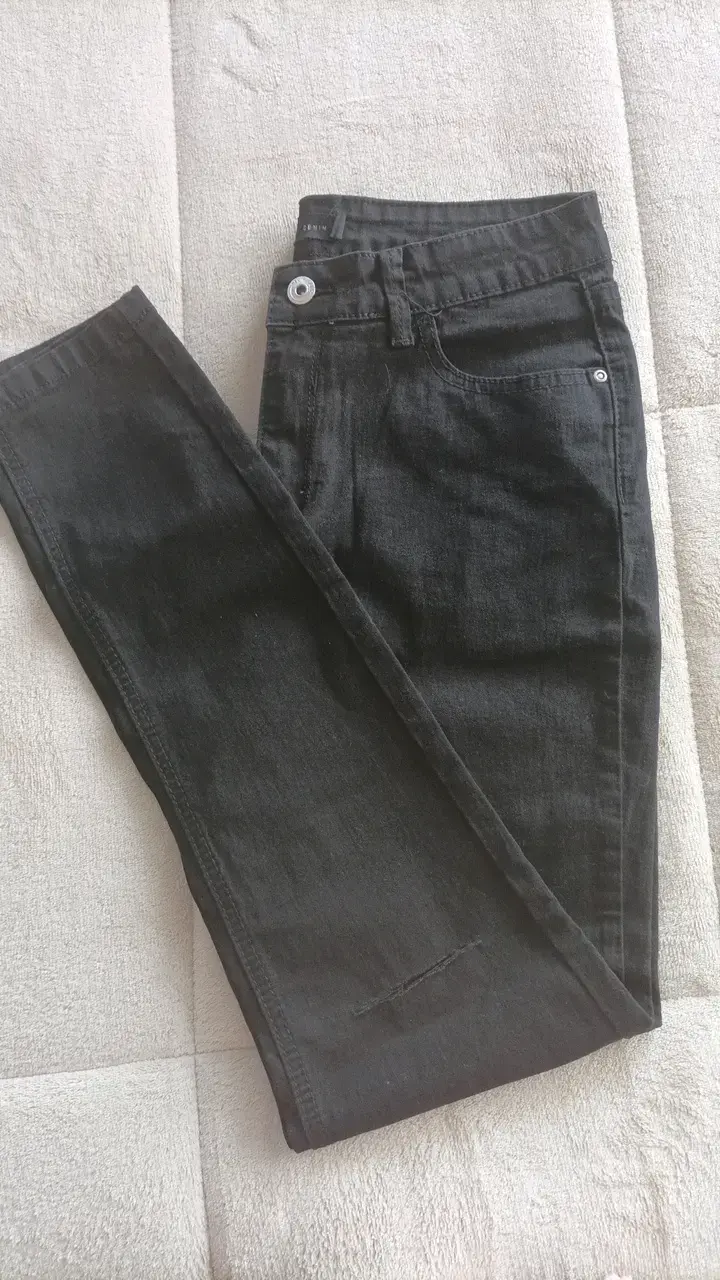 Jeans negros de mezclilla con detalles desgastados