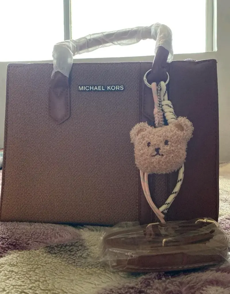 Cartera Michael Kors marrón con colgante de oso