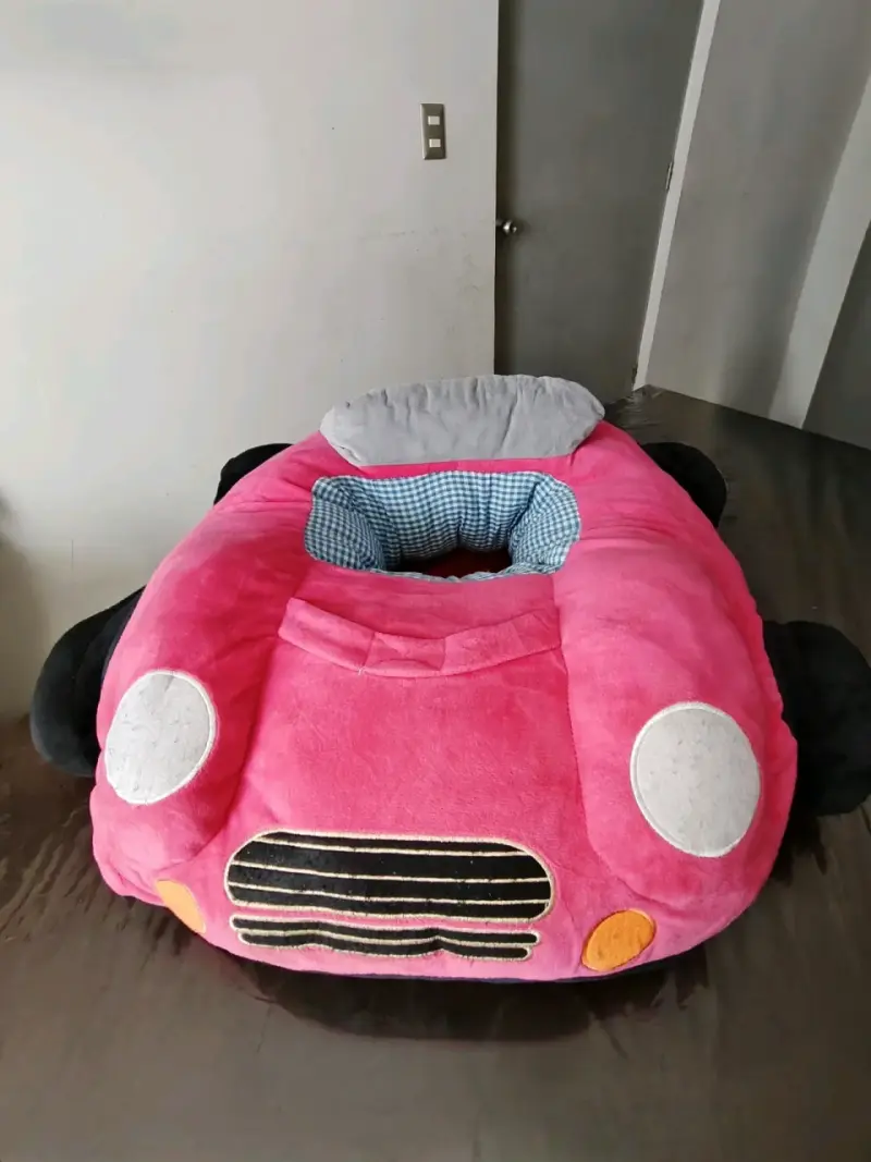 Sillón infantil en forma de auto rosado.