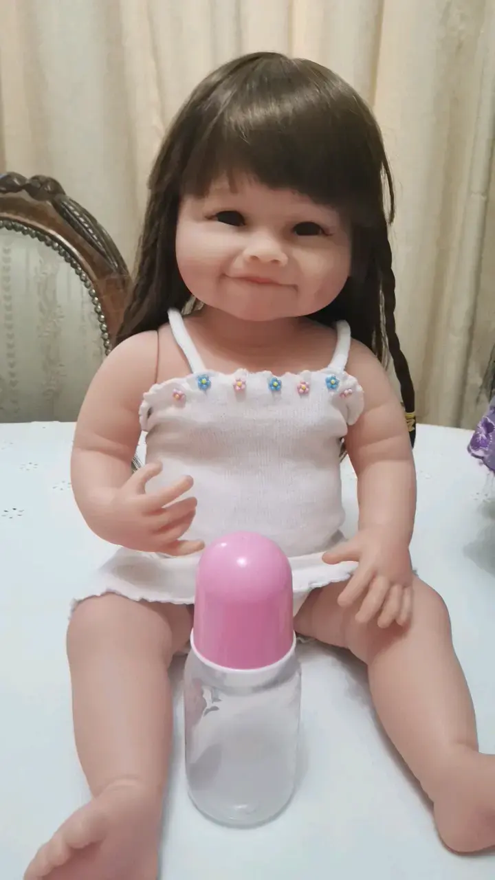 Muñeca bebé con biberón y vestido blanco