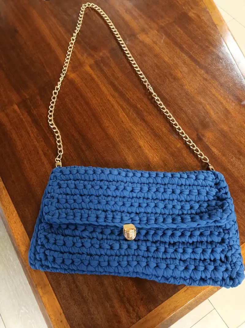Cartera de mano tejida azul con cadena dorada