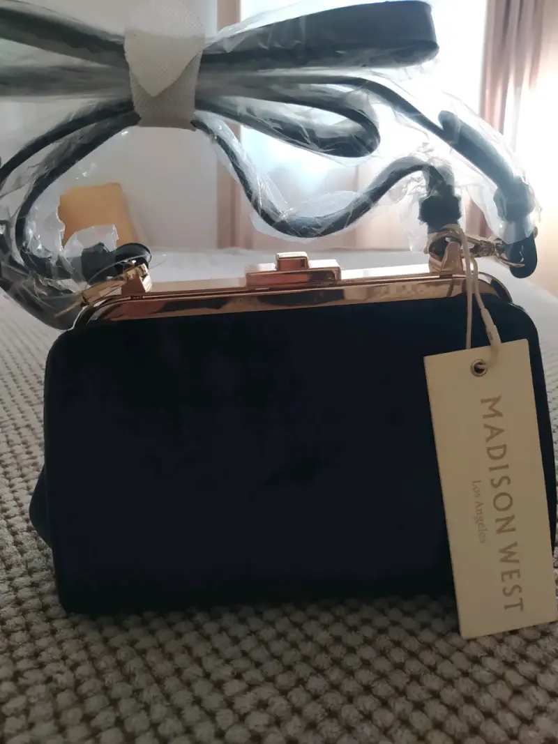 Cartera de mano negra Madison West con correa ajustable