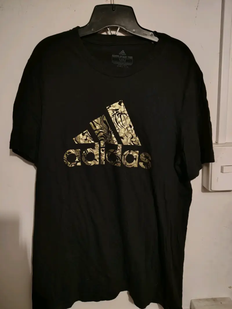 Polera negra Adidas Amplifier Tee con logo dorado - 1