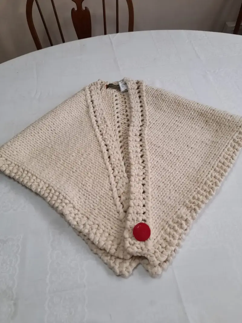 Poncho tejido a mano color crema con botón rojo