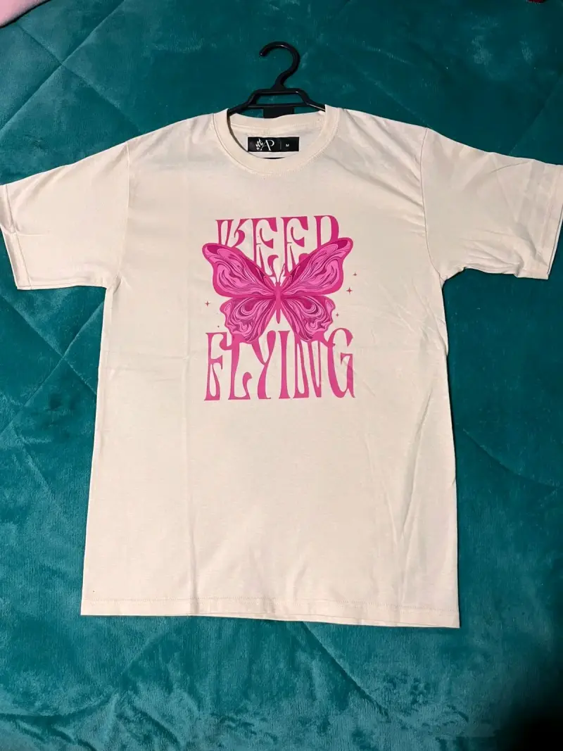 Polera beige con diseño de mariposa rosa