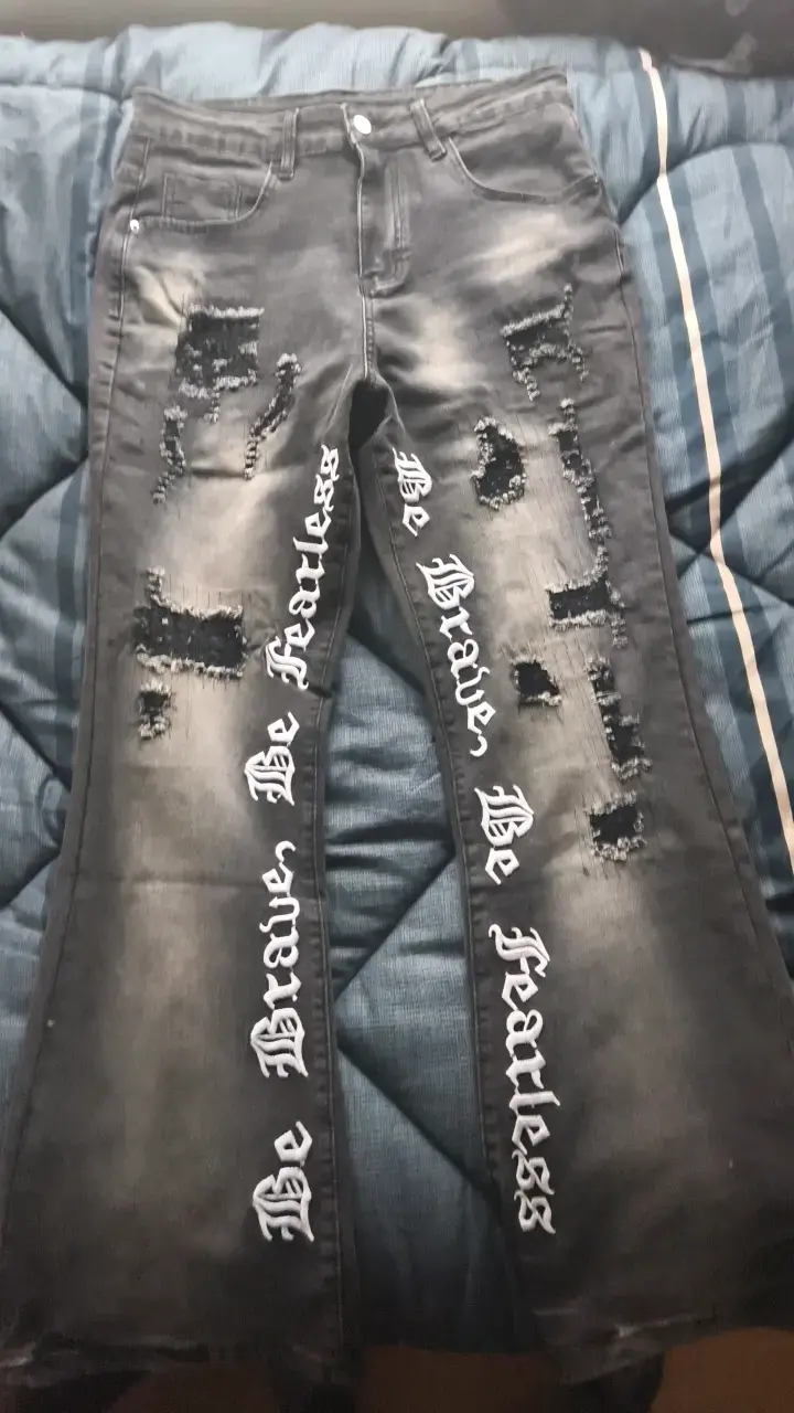 Jeans negros con diseño rasgado y texto - 1