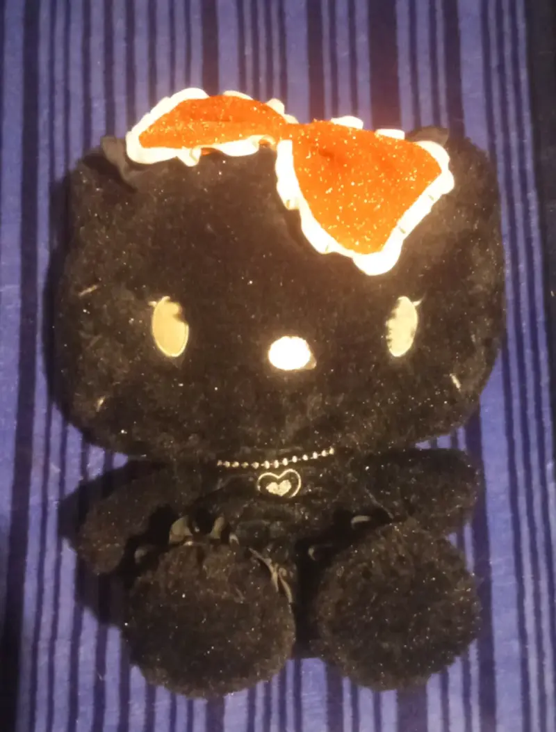 Peluche negro de Hello Kitty con lazo rojo.