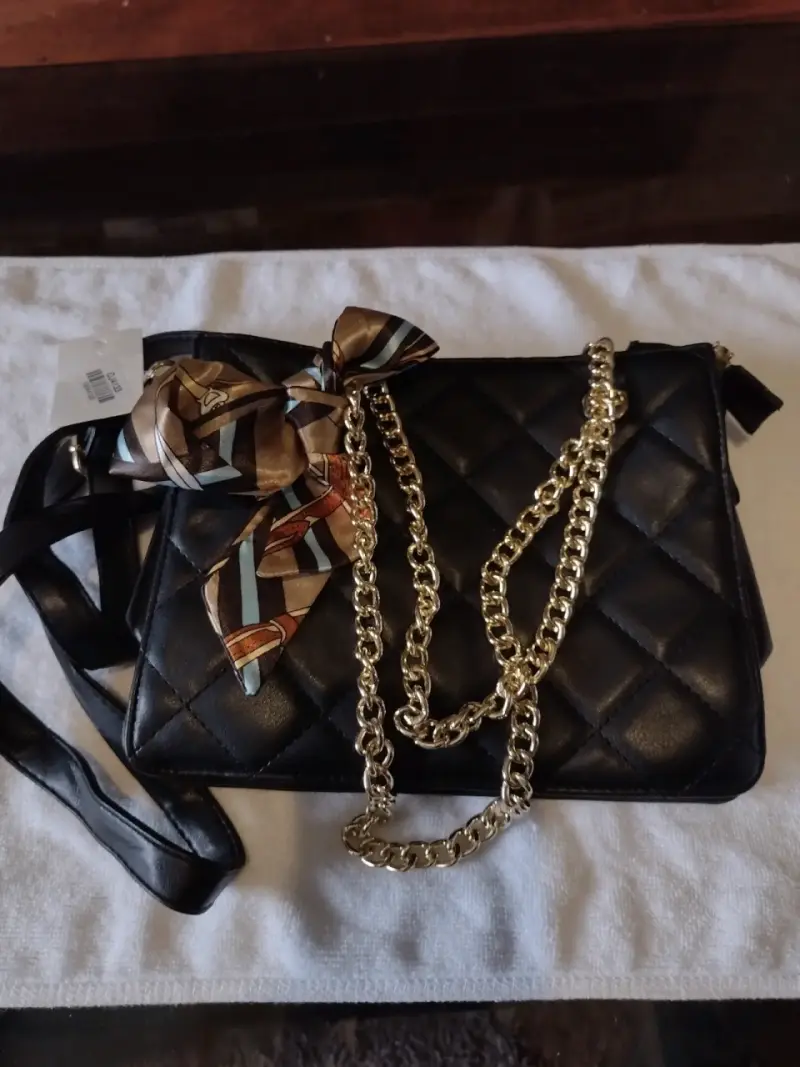 Cartera negra con cadena dorada y pañuelo decorativo