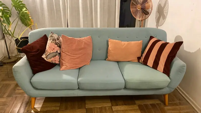 Sofá de tres plazas color celeste con cojines decorativos