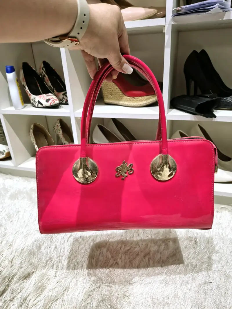 Cartera de mano fucsia con detalles dorados